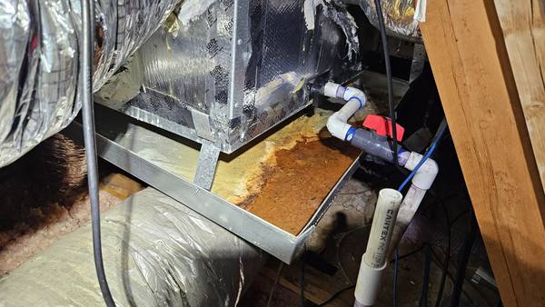 Rusted secondary drain pan under an attic air handler found during a service call