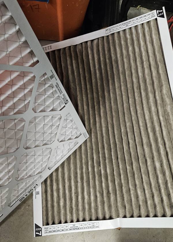 Dirty pleated air filter next to a new 20x20x1 replacement