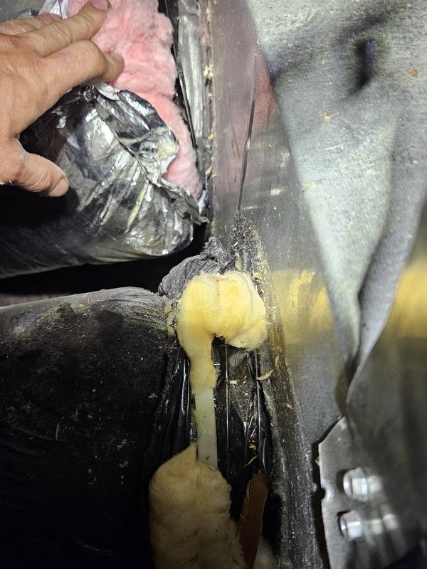 Before: leaking gap at a duct connection stuffed with old foam and insulation