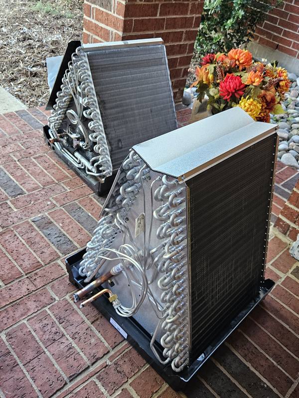 Old and new evaporator coils side by side during an AC coil replacement
