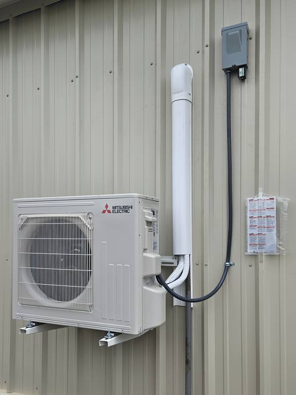 Wall-mounted Mitsubishi Electric mini-split condenser with line-set cover and disconnect