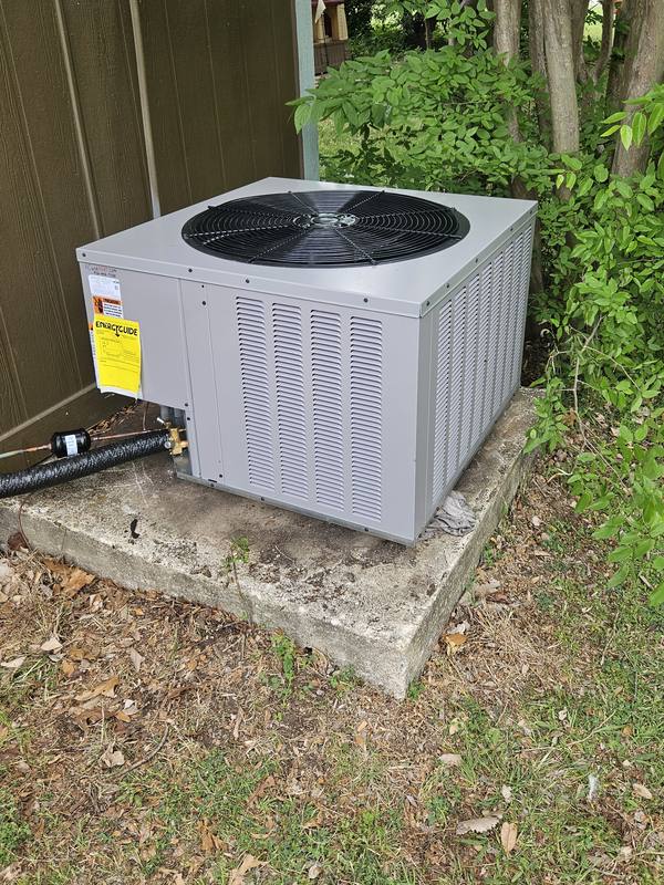Newly installed Rheem outdoor AC unit on its pad, with the EnergyGuide tag still on